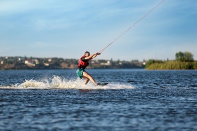 Photo of Man wakeboarding on river. Extreme water sport