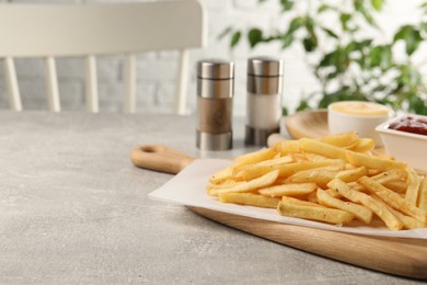 Photo of Delicious french fries on light grey table, space for text
