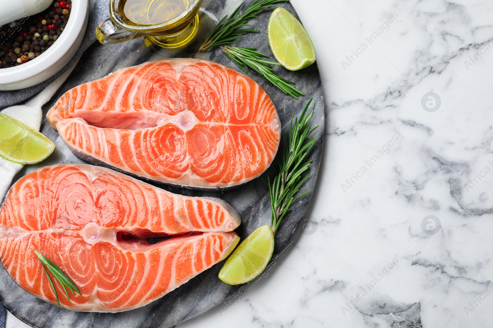 Photo of Top view of fresh raw salmon and products on white marble table. Fish delicacy