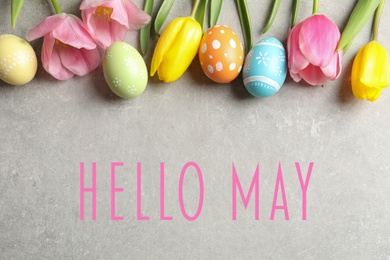 Image of Hello May. Flat lay composition of painted Easter eggs and spring flowers on grey background