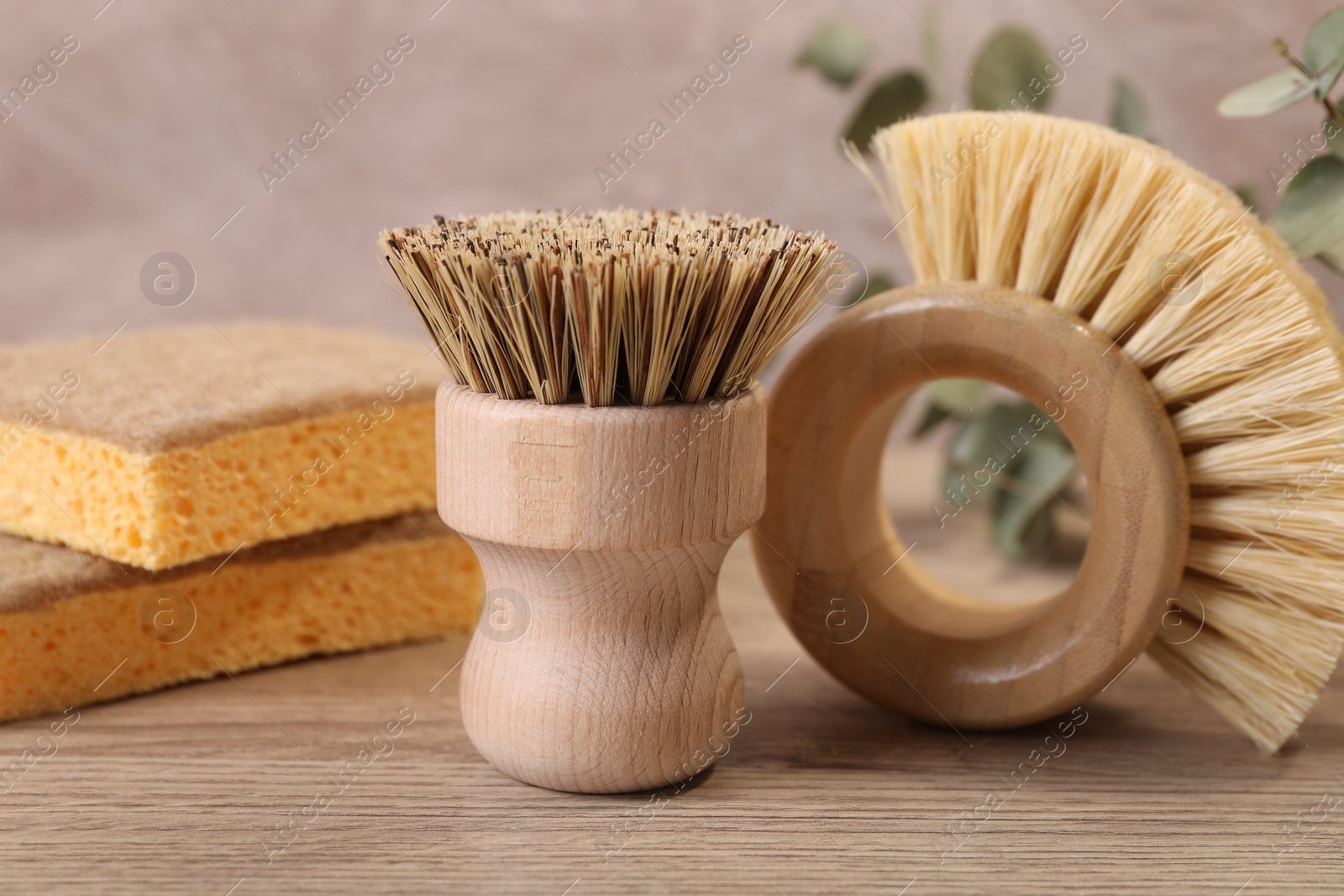 Photo of Small cleaning brushes and sponges on wooden table, closeup