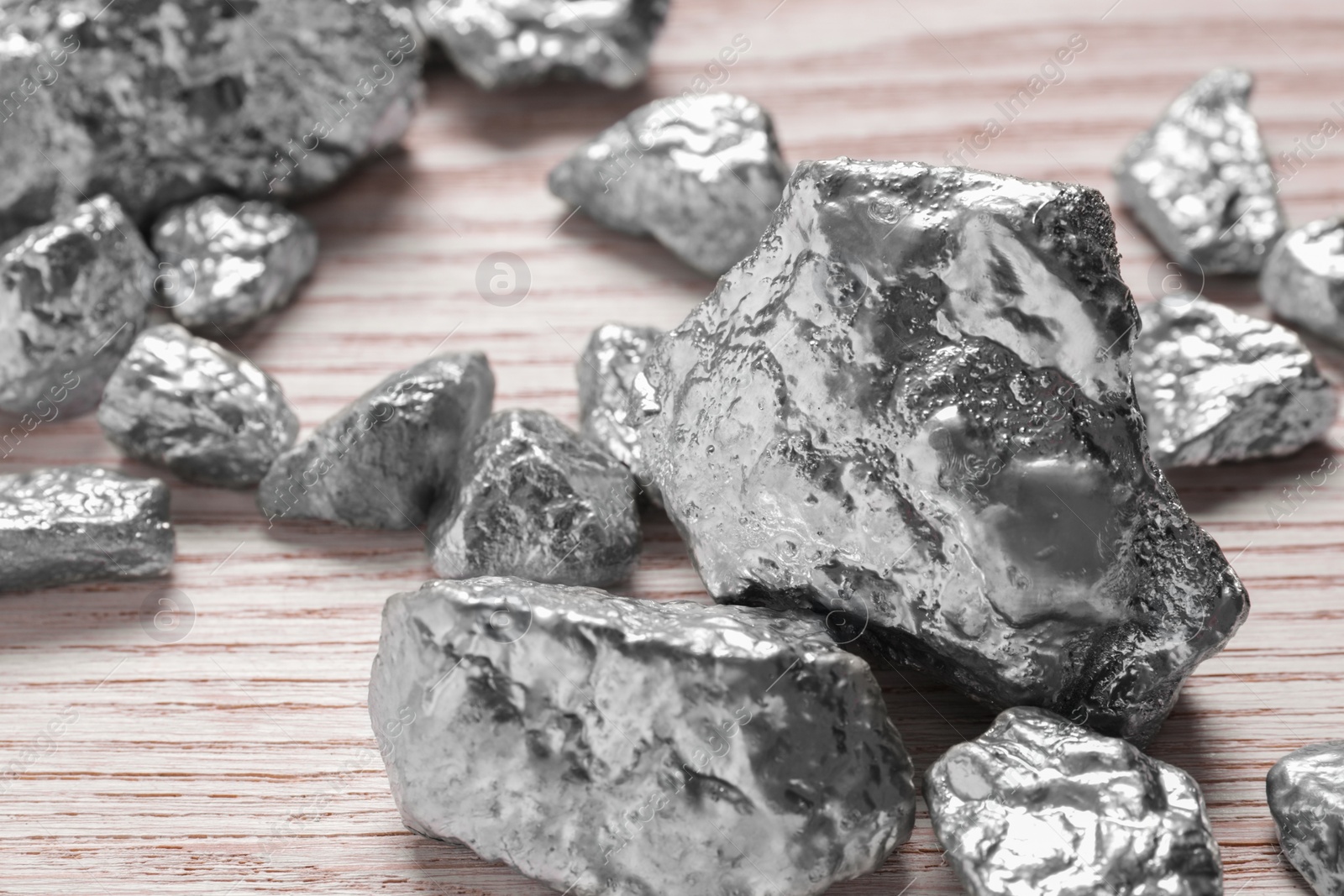 Photo of Pile of silver nuggets on white wooden table, closeup