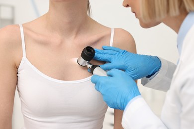 Photo of Dermatologist with dermatoscope examining patient, closeup view