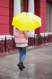 Woman with umbrella taking autumn walk in city on rainy day