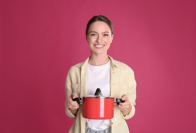 Photo of Happy woman with pot on crimson background