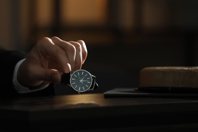 Man putting luxury wrist watch on table, closeup. Space for text