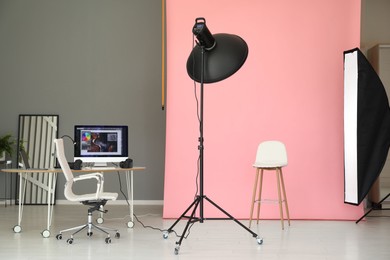 Photo of Pink photo background, workplace and professional lighting equipment in modern studio