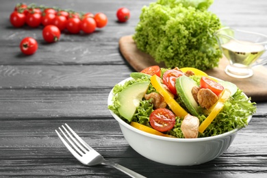 Photo of Delicious fresh chicken salad served on black wooden table. Space for text