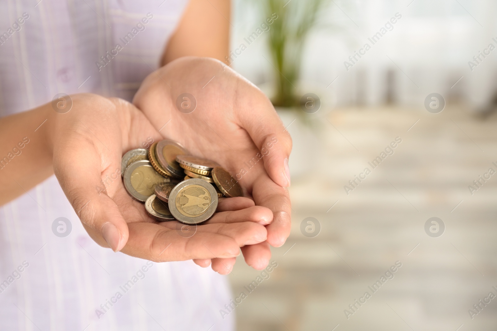 Photo of Young woman with handful of coins indoors, closeup view. Space for text