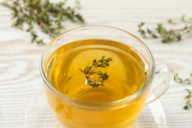 Photo of Aromatic herbal tea with thyme on white wooden table, closeup
