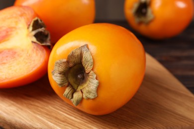 Photo of Whole and cut delicious ripe persimmons on wooden table, closeup