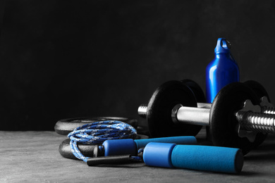Photo of Gym equipment and accessories on stone floor against dark background