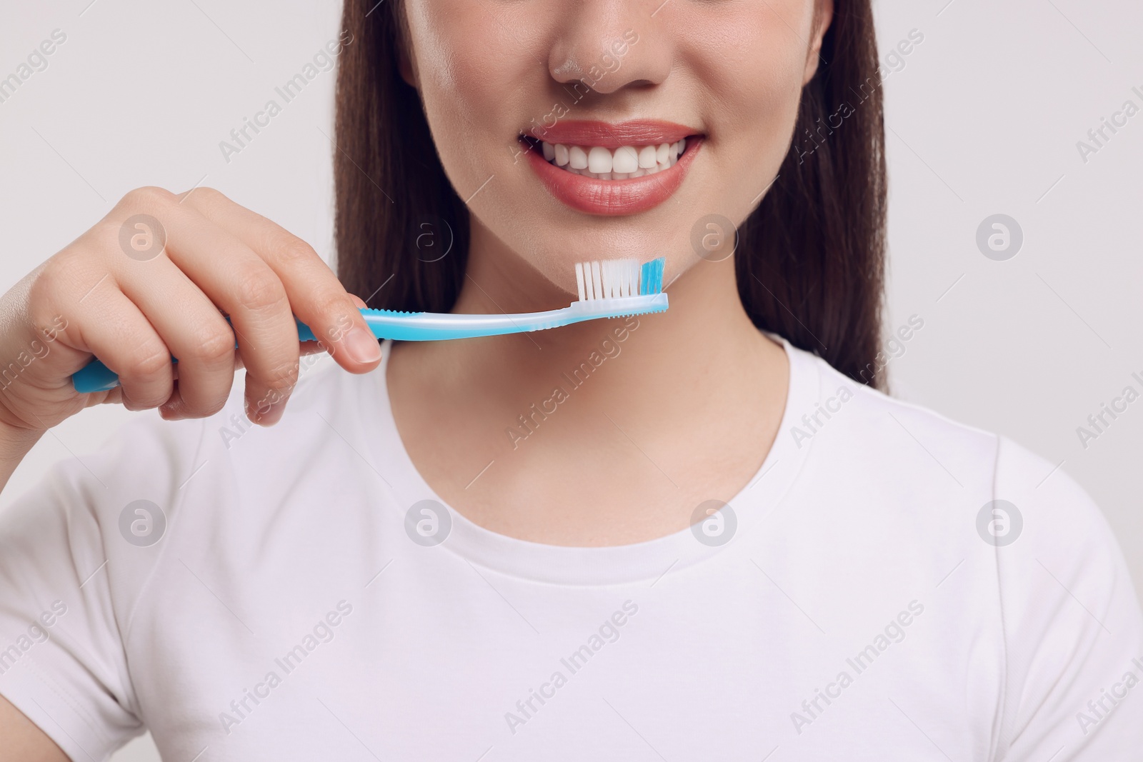 Photo of Woman holding plastic toothbrush on white background, closeup