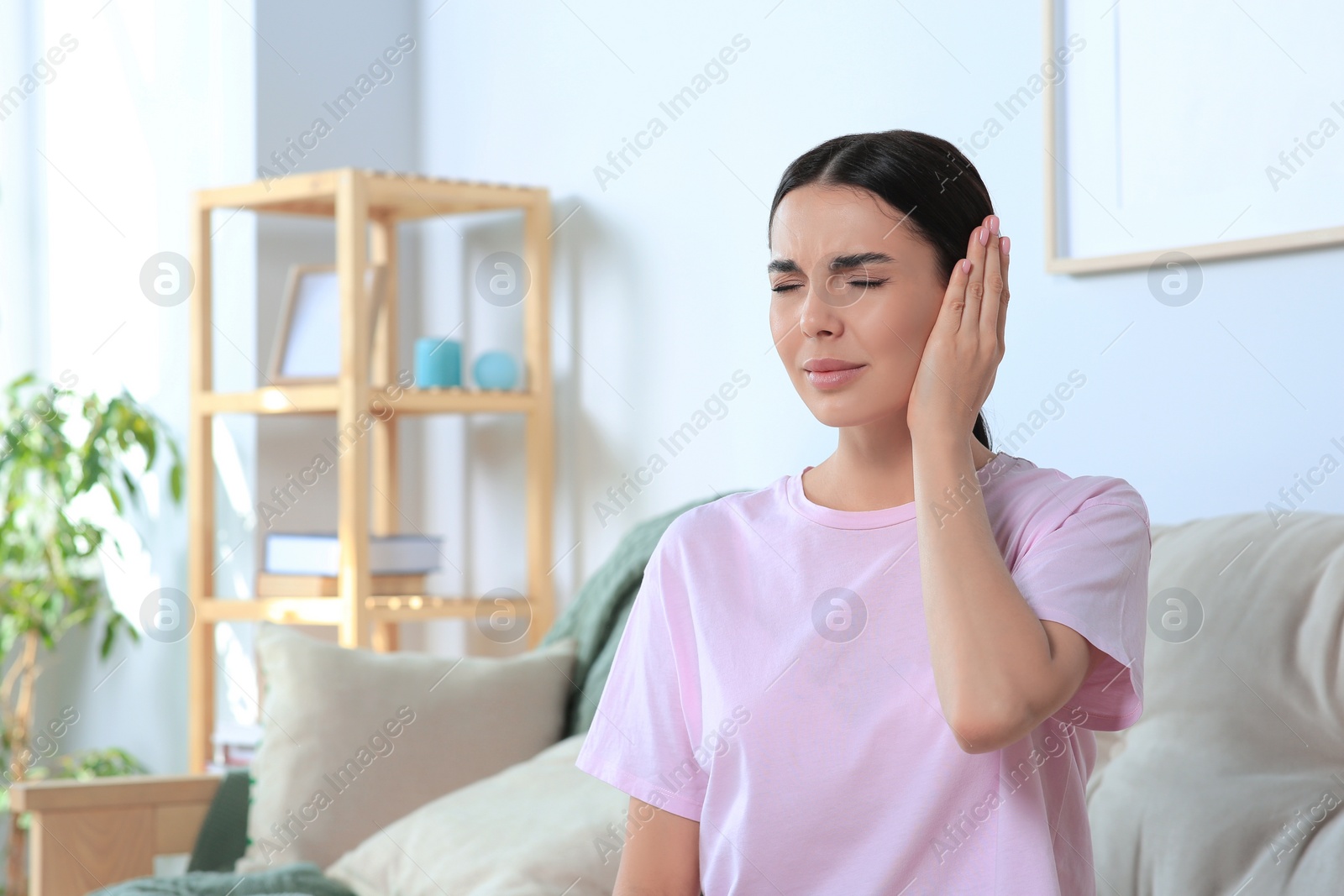 Photo of Young woman suffering from ear pain at home