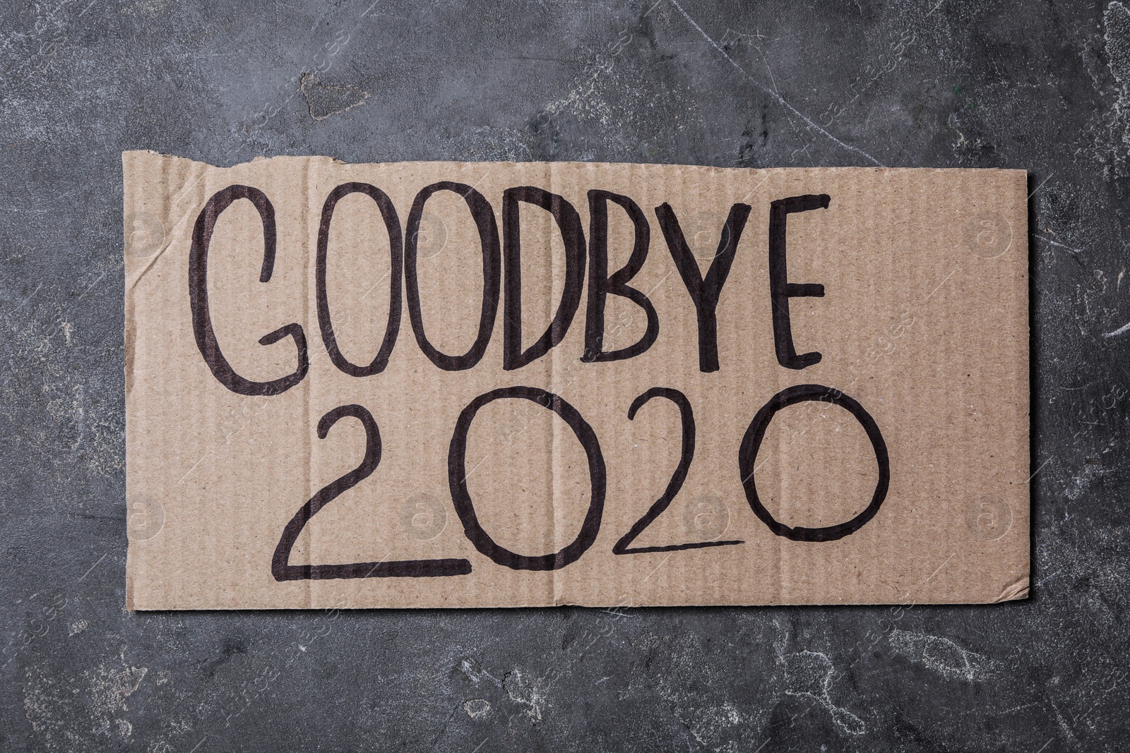 Photo of Cardboard with text Goodbye 2020 on grey stone background, top view