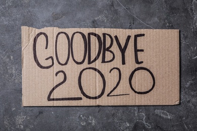 Photo of Cardboard with text Goodbye 2020 on grey stone background, top view