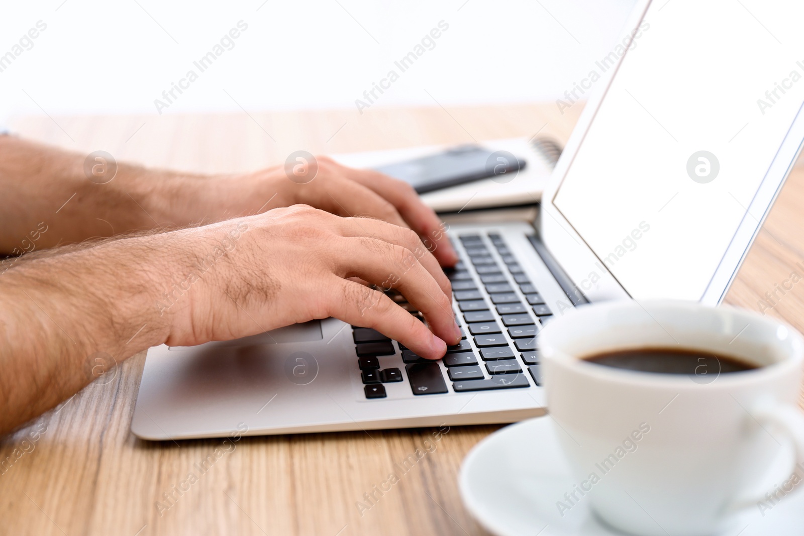 Photo of Man working with modern laptop at wooden table, closeup