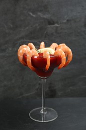 Photo of Delicious shrimp cocktail with tomato sauce served on black table