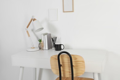 Photo of Comfortable workplace with white desk near wall at home