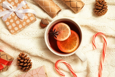 Flat lay composition with cup of hot winter drink on warm knitted plaid. Cozy season