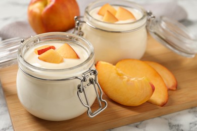 Photo of Delicious yogurt with fresh peach on white marble table, closeup