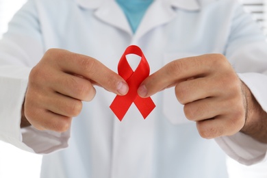 Photo of Doctor holding red awareness ribbon, closeup. World Aids day