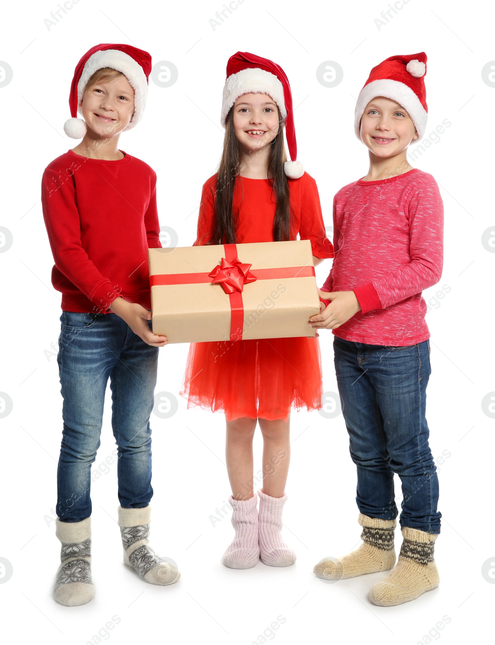 Photo of Cute little children in Santa hats with Christmas gift box on white background