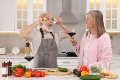 Photo of Affectionate senior couple having fun while cooking together in kitchen