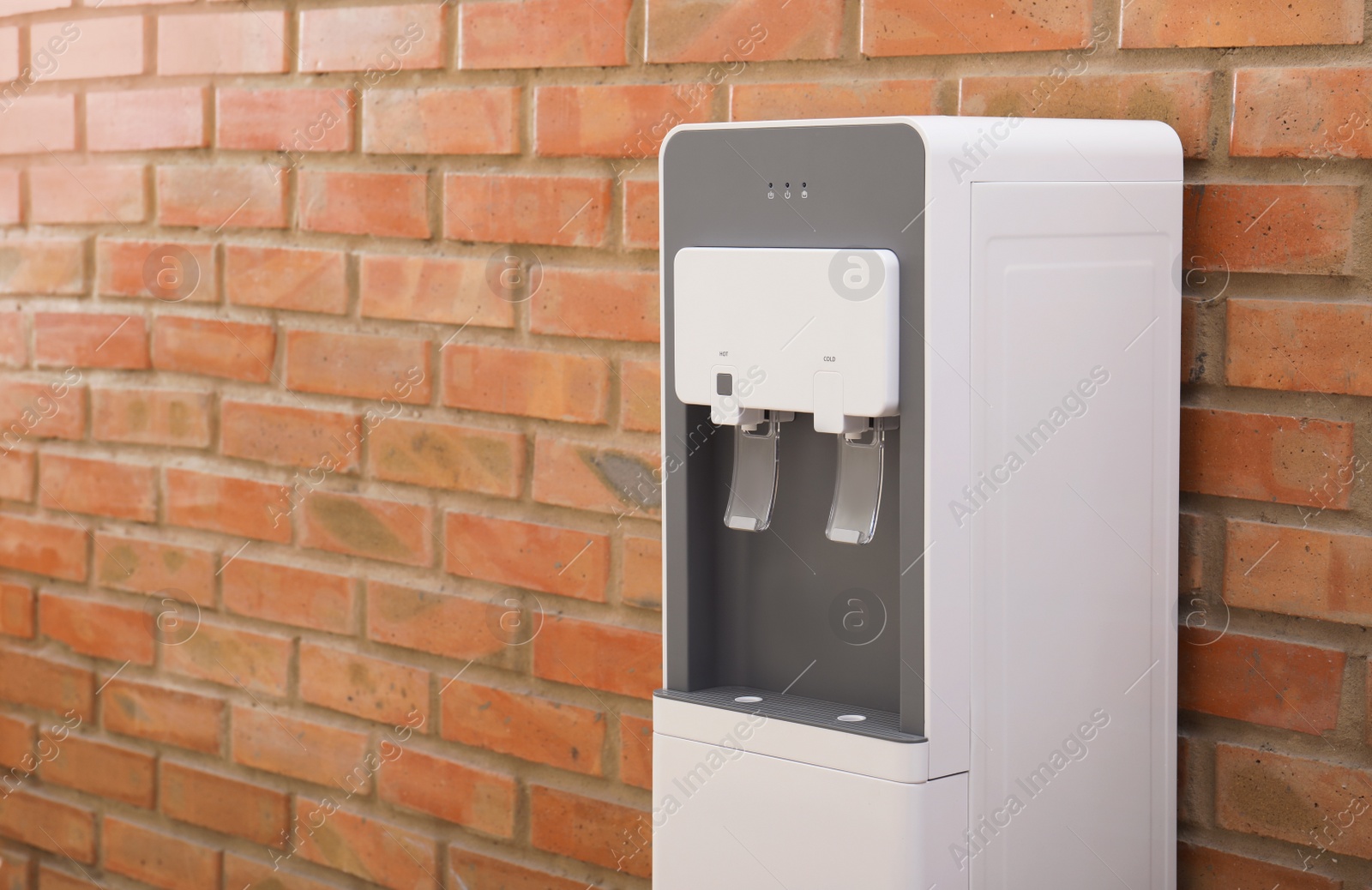 Photo of Modern water cooler near brick wall