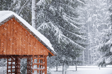 Photo of Modern wooden gazebo on snowy day. Winter vacation