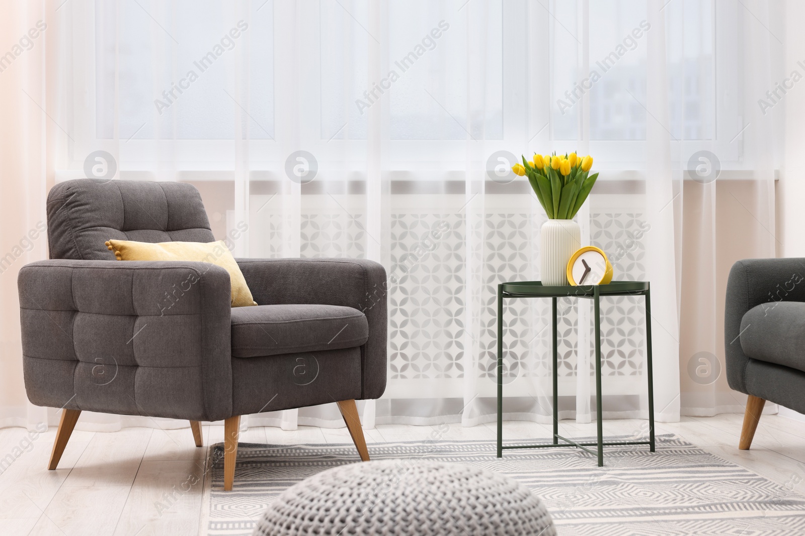 Photo of Spring atmosphere. Stylish living room interior with comfortable furniture and bouquet of beautiful yellow tulips