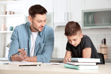 Photo of Dad helping his son with homework in kitchen