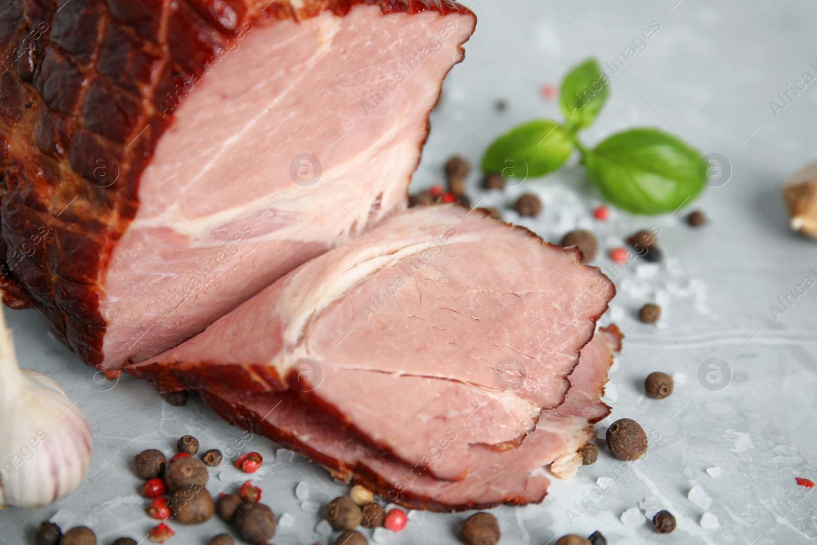 Photo of Delicious ham with spices, garlic and basil on grey marble table, closeup