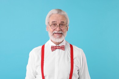 Portrait of stylish grandpa with glasses and bowtie on light blue background