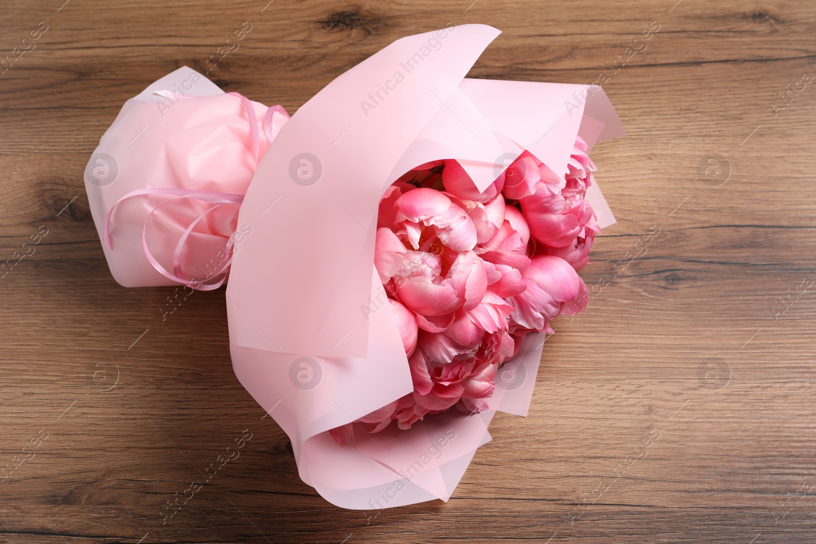 Photo of Bouquet of beautiful pink peonies on wooden table, top view