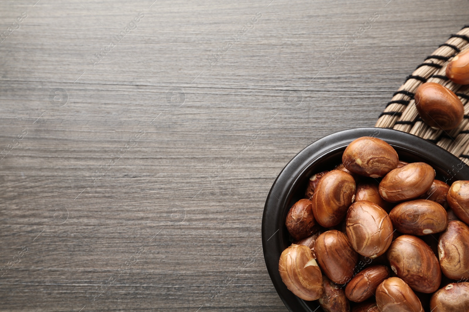 Photo of Bowl with jackfruit seeds on wooden table, flat lay. Space for text