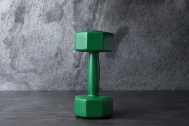 Photo of Green vinyl dumbbell on table against grey background