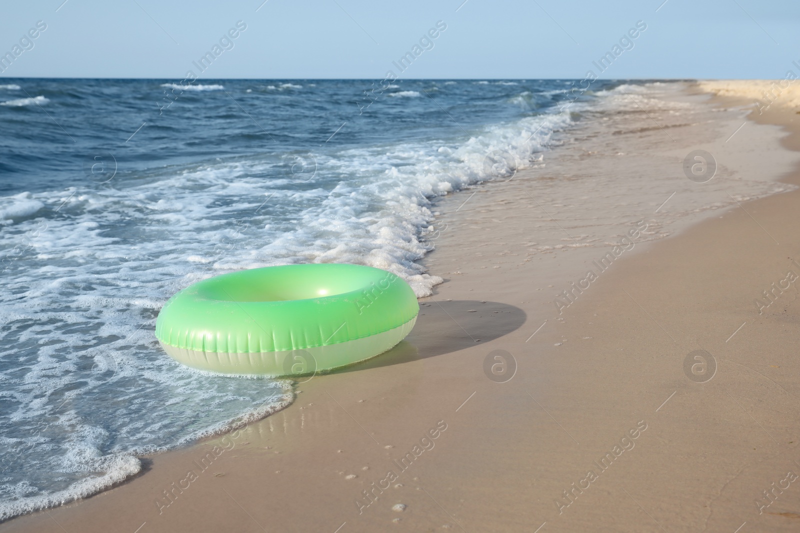 Photo of Green inflatable ring on sandy beach near sea, space for text