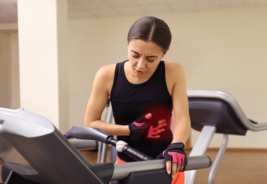 Young woman having heart attack on treadmill in gym