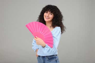 Photo of Happy woman holding hand fan on light grey background