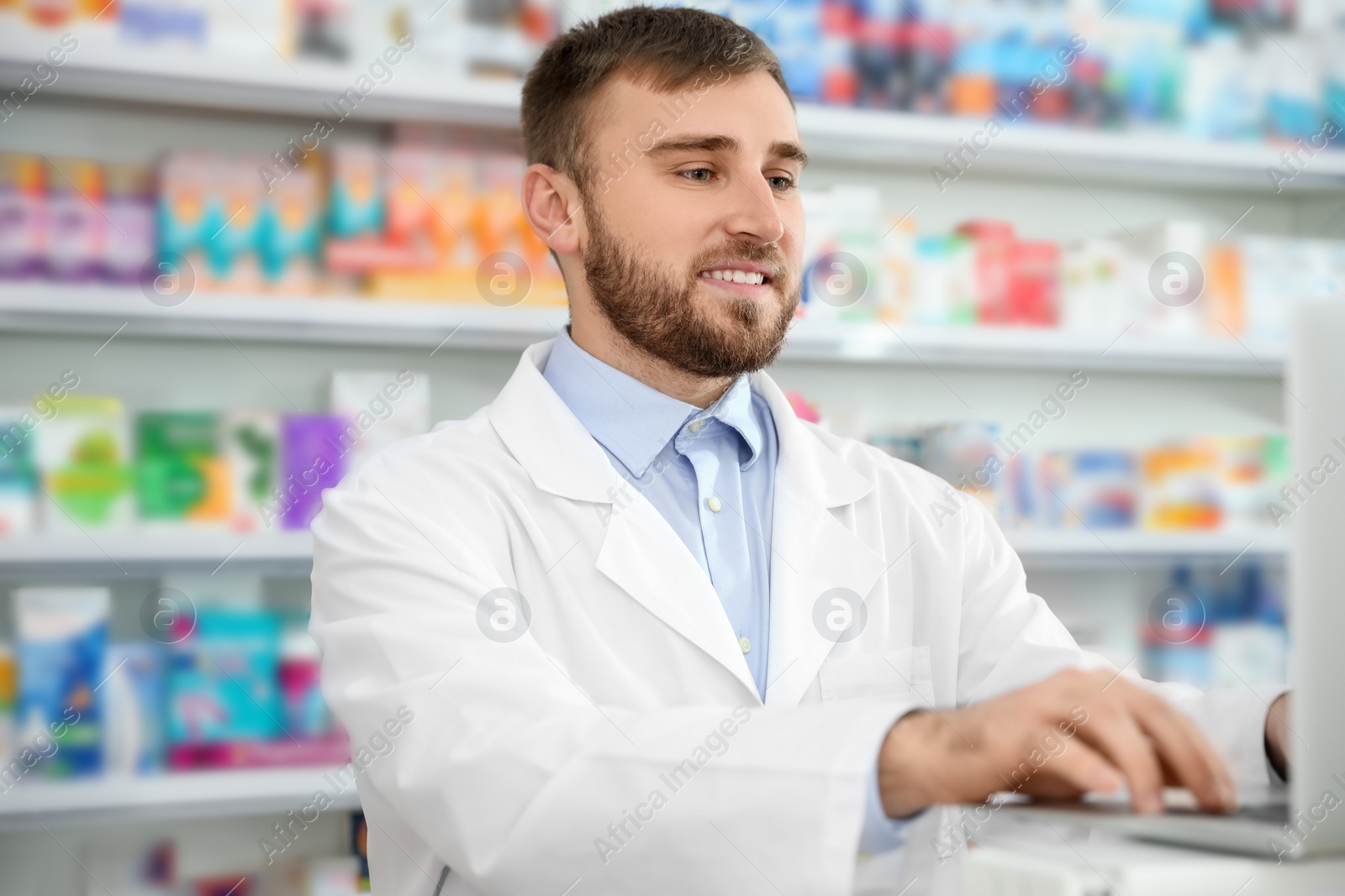 Photo of Professional pharmacist working on laptop in modern drugstore