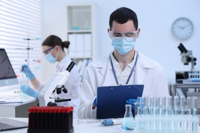 Photo of Scientist working with laboratory test form at table indoors