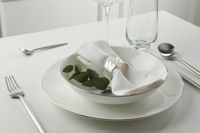 Stylish setting with cutlery and napkin on white textured table