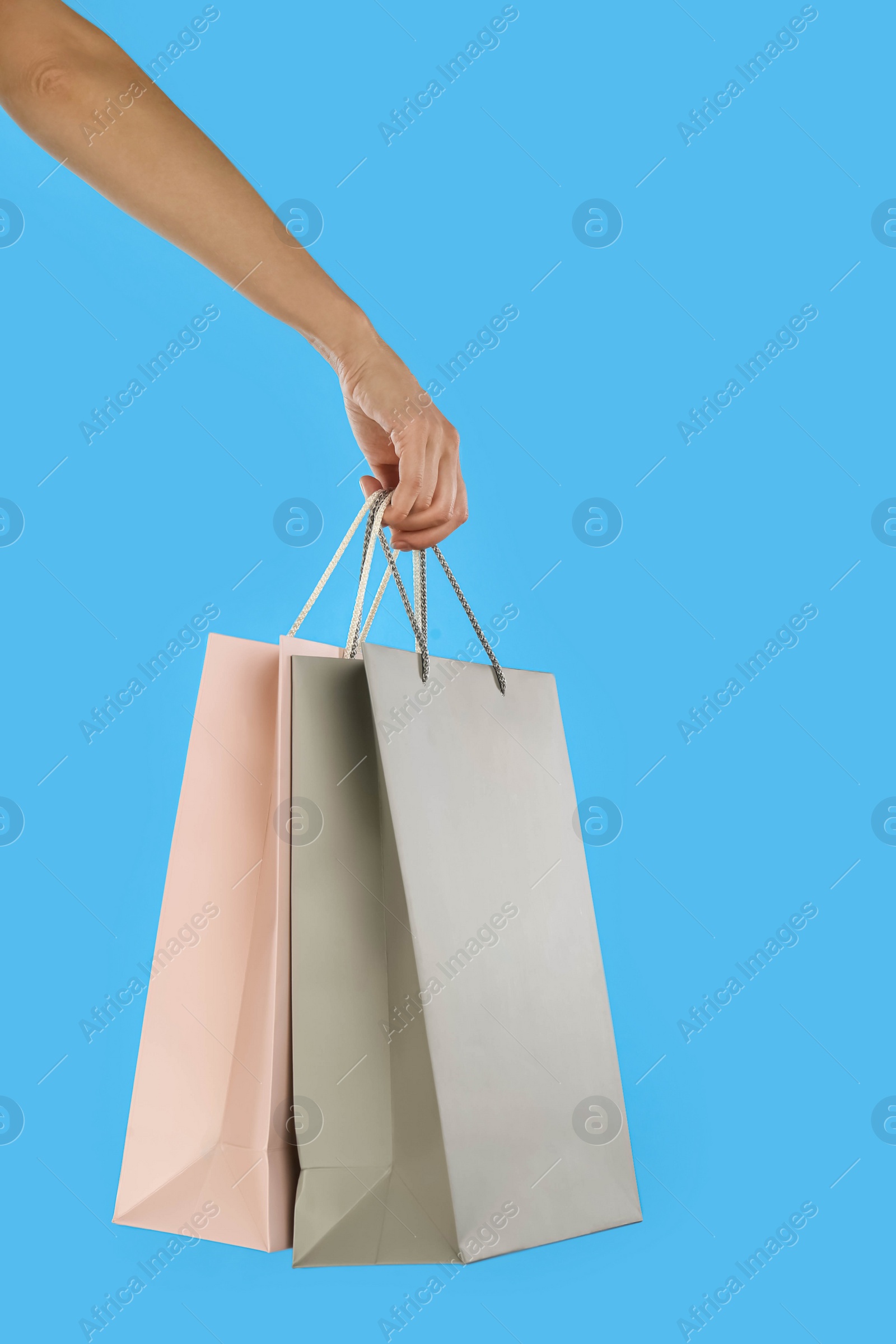 Photo of Woman with paper shopping bags on light blue background, closeup