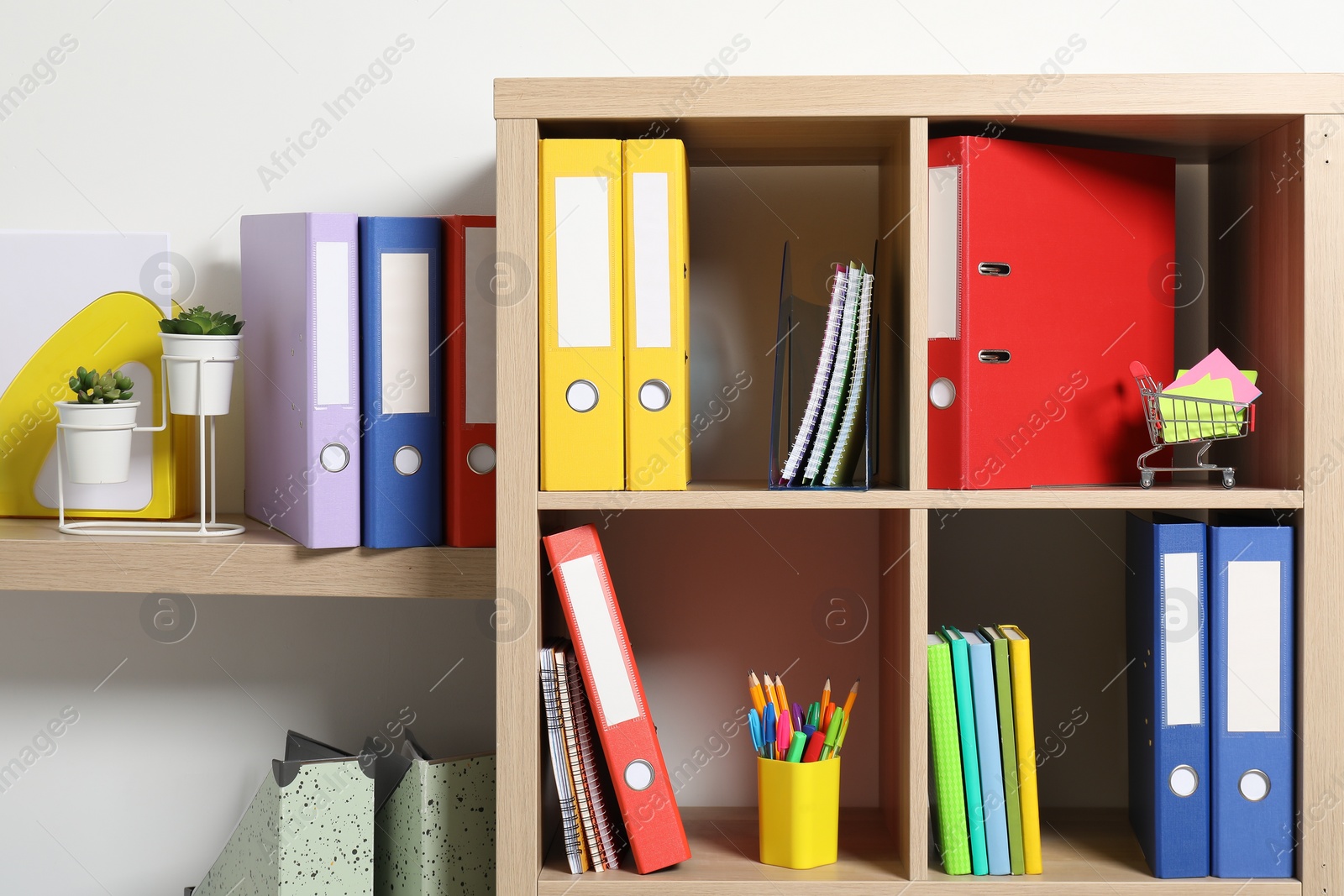 Photo of Colorful binder office folders and other stationery on shelving unit indoors