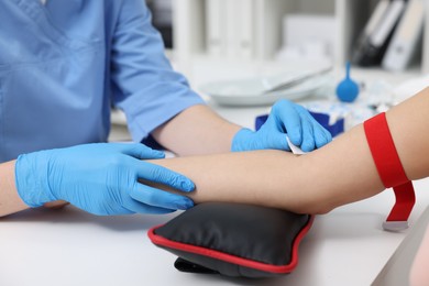 Photo of Laboratory testing. Doctor taking blood sample from patient at white table in hospital, closeup