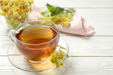 Cup of tea and linden blossom on white wooden table