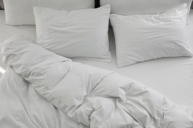 Many soft pillows and blanket on large comfortable bed