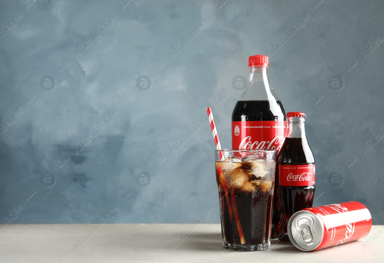 Photo of MYKOLAIV, UKRAINE - NOVEMBER 15, 2018: Bottles, glass and can with Coca Cola on table against color background. Space for text