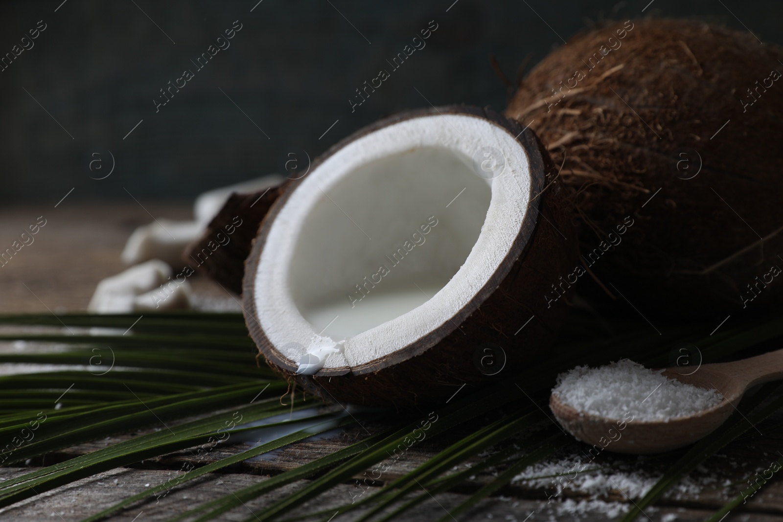 Photo of Coconut milk, flakes, nuts and palm leaf on wooden table, closeup. Space for text